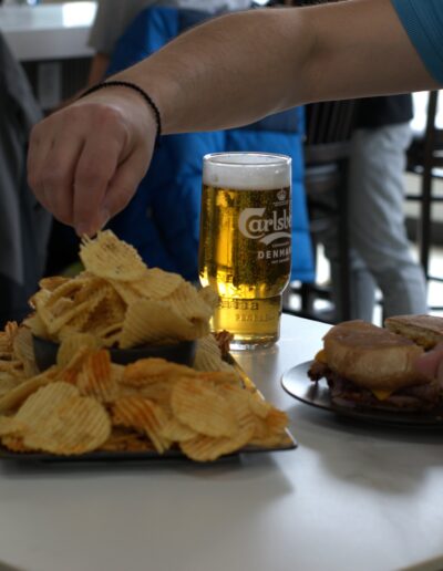 Blue shirt reaching for chips with carlsberg